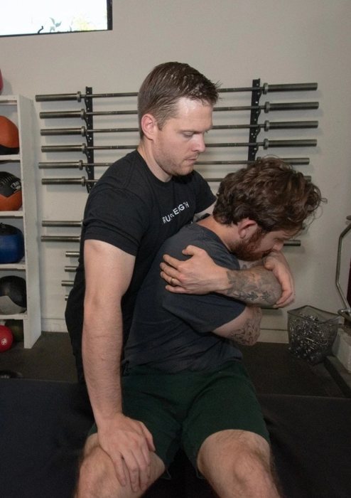 A therapist assessing a patient's back in the gym